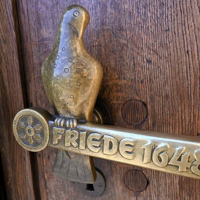Die Tür zum Rathaus ziert eine Friedenstaube und das Jahr des Friedensschlusses 1648.
